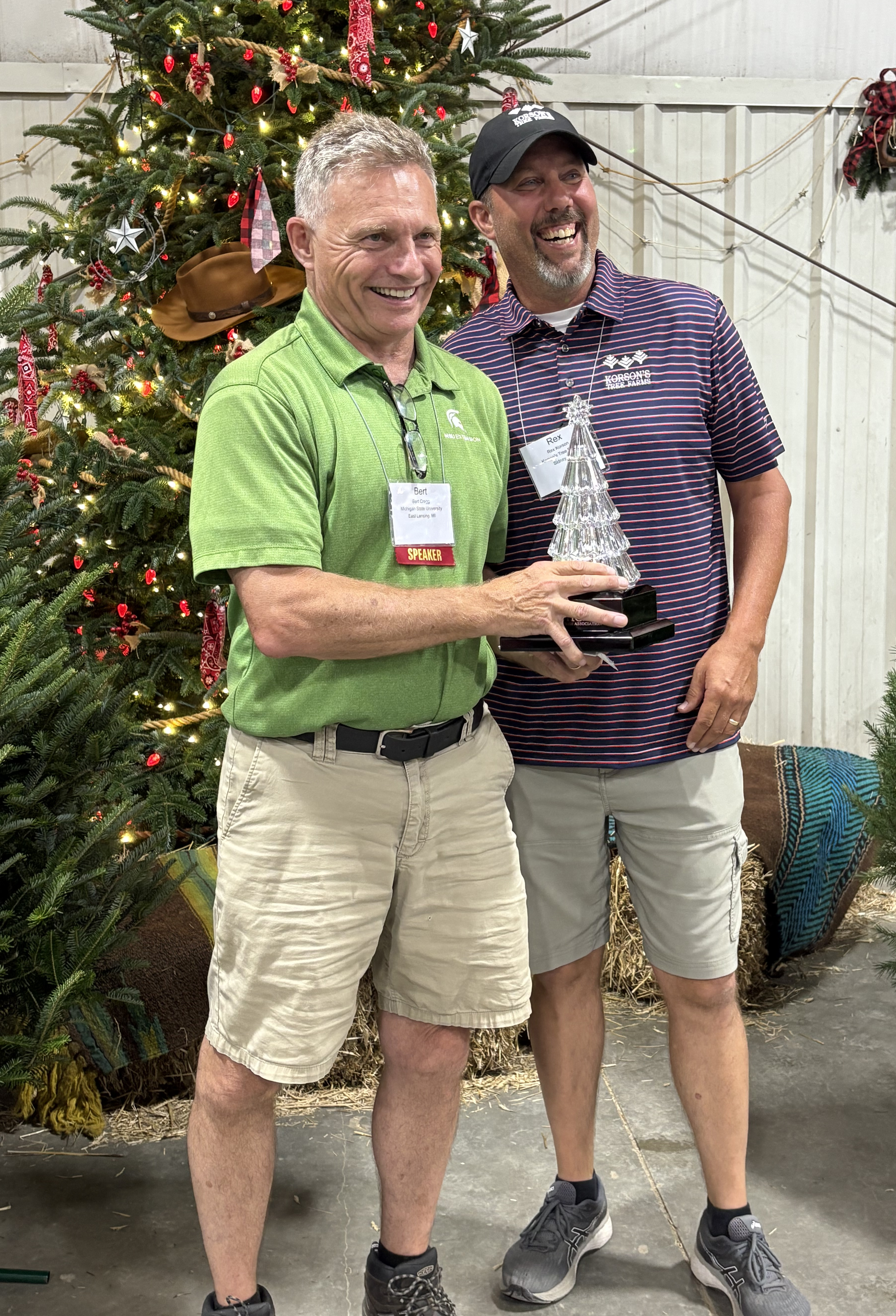 Bert and Rex pose for a picture in front of Christmas trees.